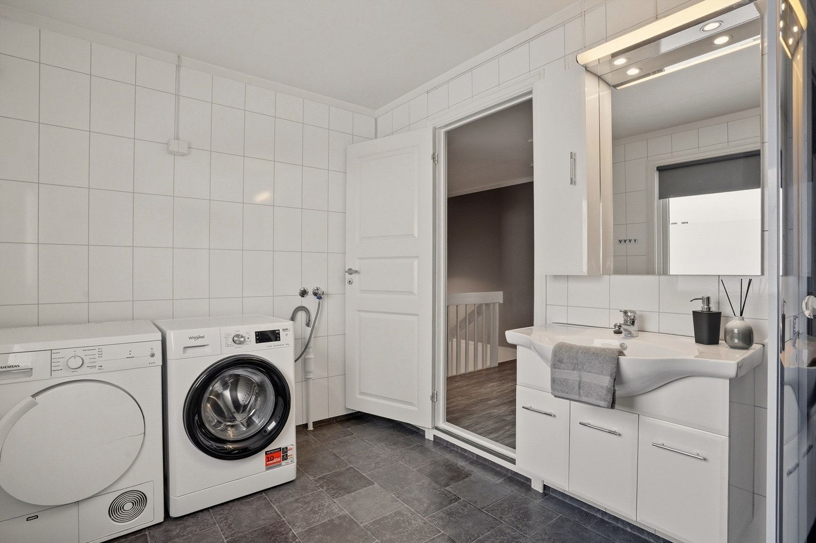 Badet innredet med dusjkabinett og opplegg for vaskemaskin og tørketrommel. Galleribilde