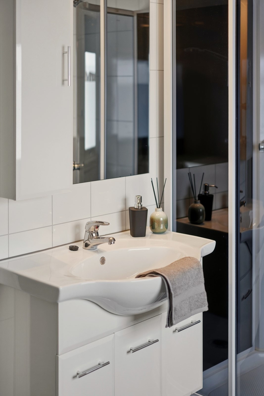 Baderomsinnredningen er hvit med nedfelt servant med rom for oppbevaring og speil. Galleribilde