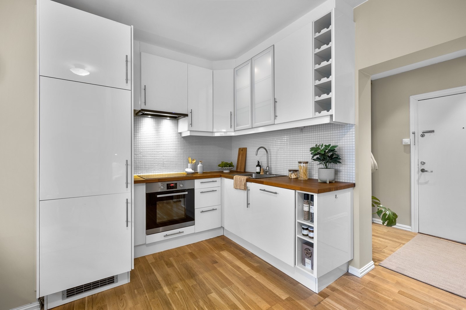 Kjøkkeninnredning med under-/overskap og slette fronter, benkeplate av heltre med nedfelt kum i rustfritt stål og ett-greps blandebatteri. Galleribilde