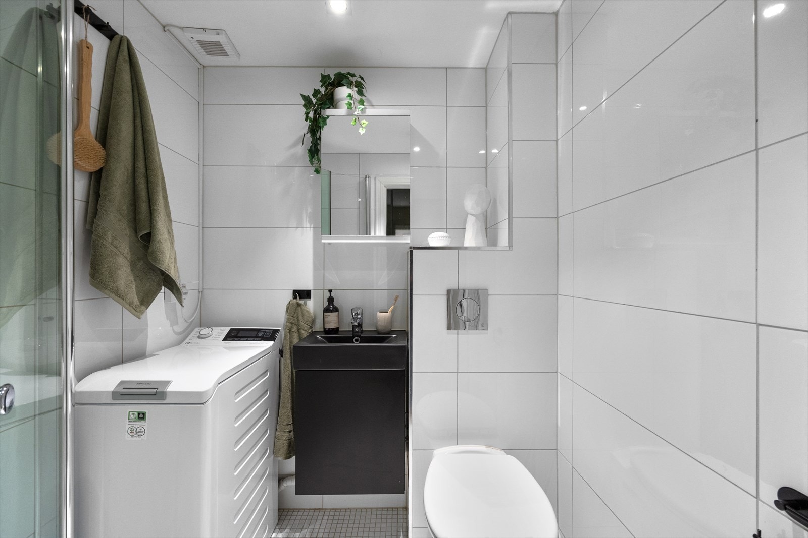 Badet er fra 2011/2012 og innredningen består av servantskap, speilskap, vegghengt toalett og avskjermet dusjhjørne. Det er opplegg for vaskemaskin. Galleribilde