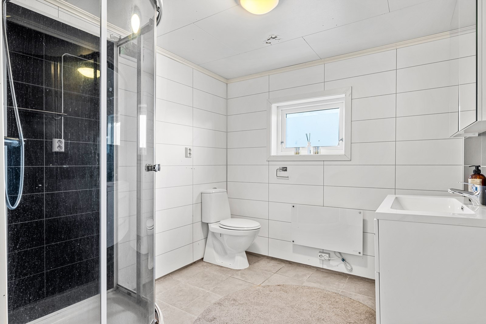 Badet med flislagt gulv og panelplater på vegg. Galleribilde