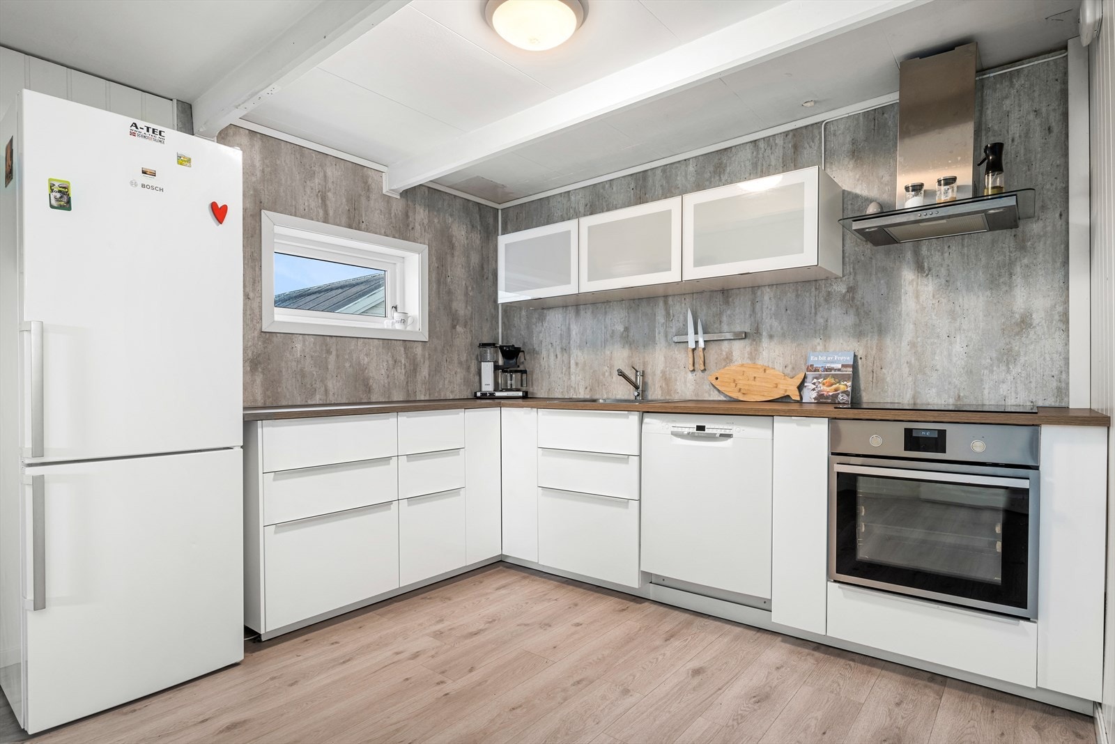 Smakfullt hjørnekjøkken med laminat på gulv og med mye skap- og benkeplass. Galleribilde