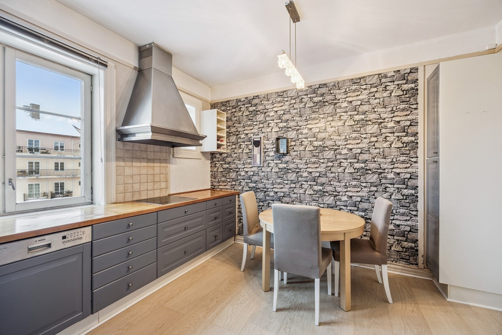 Kjøkken med spiseplass og kjøkkeninnredning m/nedfelt induksjonstopp, integrert oppvaskmaskin og stekeovn. Løst side by side kjøl/frys i egen nisje. Galleribilde