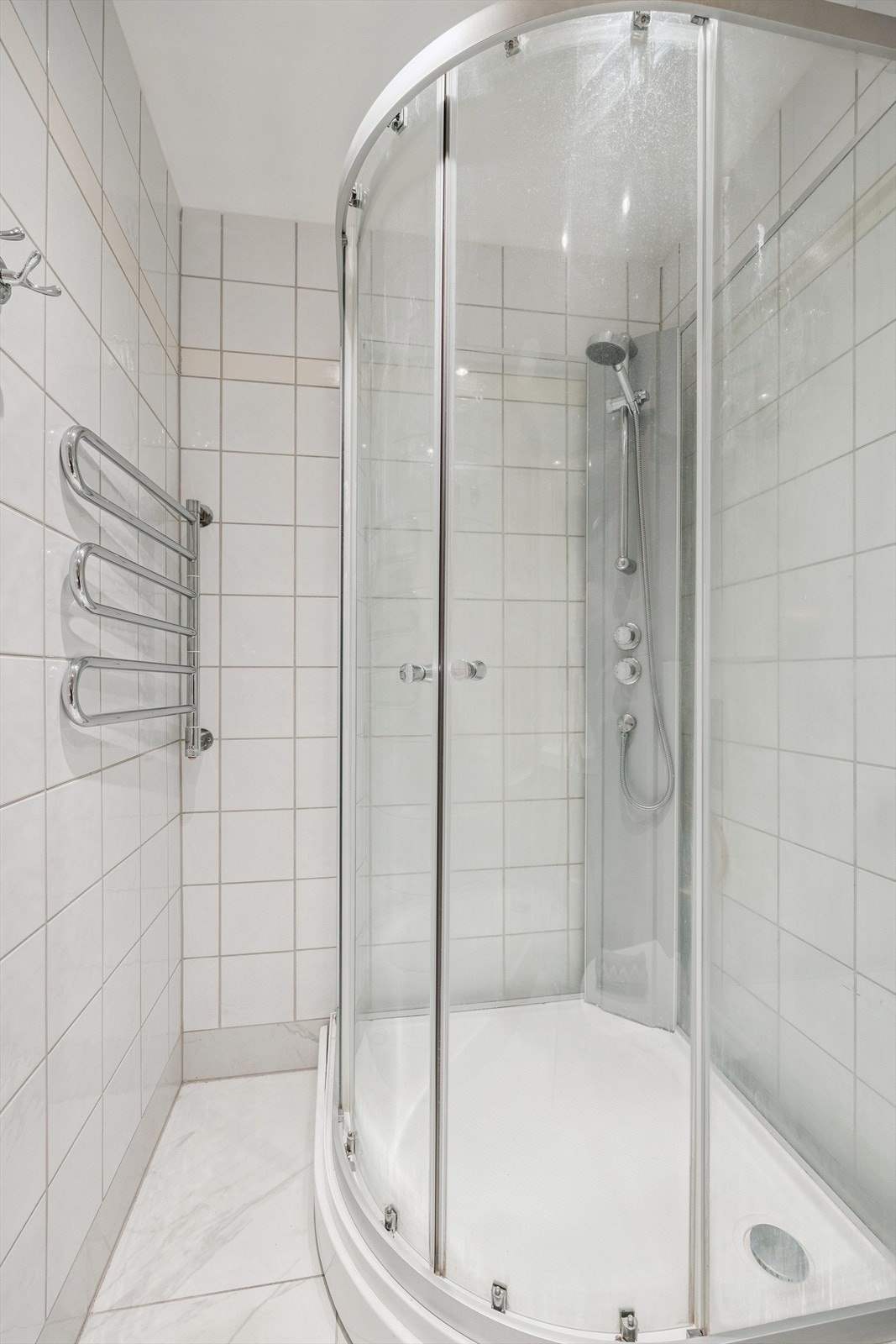 Bad med med nedfelt servant, veggmontert toalett, dusjkabinett og flislagt gulv med elektriske varmekabler. Oppgradert i 2023. Galleribilde