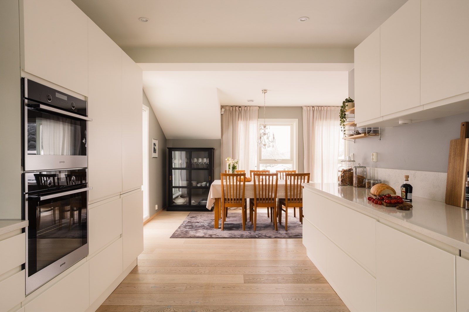 Innredning fra Italienske Aran cucine med lyse slette fronter og lekker benkeplate + backsplash i kompositt. Galleribilde