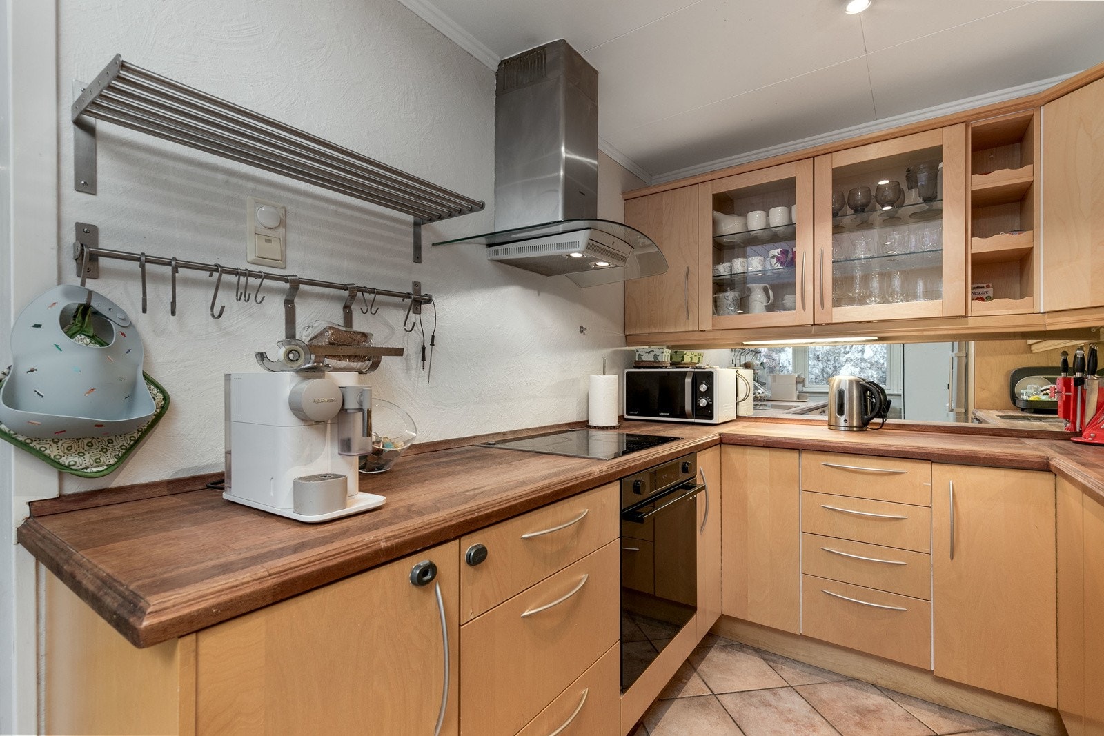 Mellom over- og underskap er det montert speil, samt belysning under overskap. Av utstyr medfølger integrerte hvitevarer som stekeovn, platetopp og oppvaskmaskin. Galleribilde