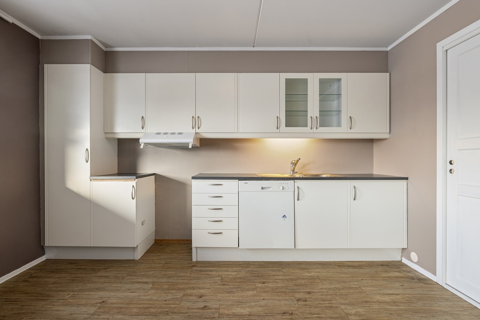 Kjøkkenet har innredning med glatte fronter. Benkeplaten er av laminat. Det er kjøkkenventilator med avtrekk ut. Oppvaskmaskin medfølger. Galleribilde