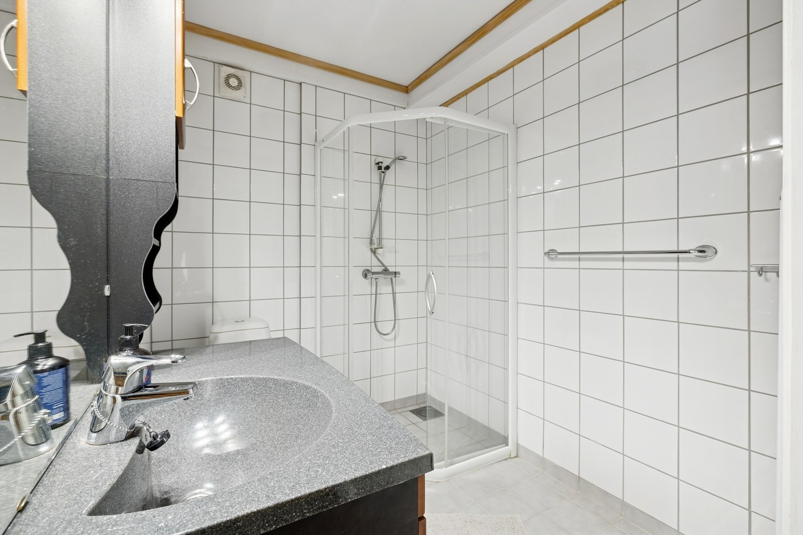 Bad innredet med dusj, toalett og servant med innredning. Galleribilde