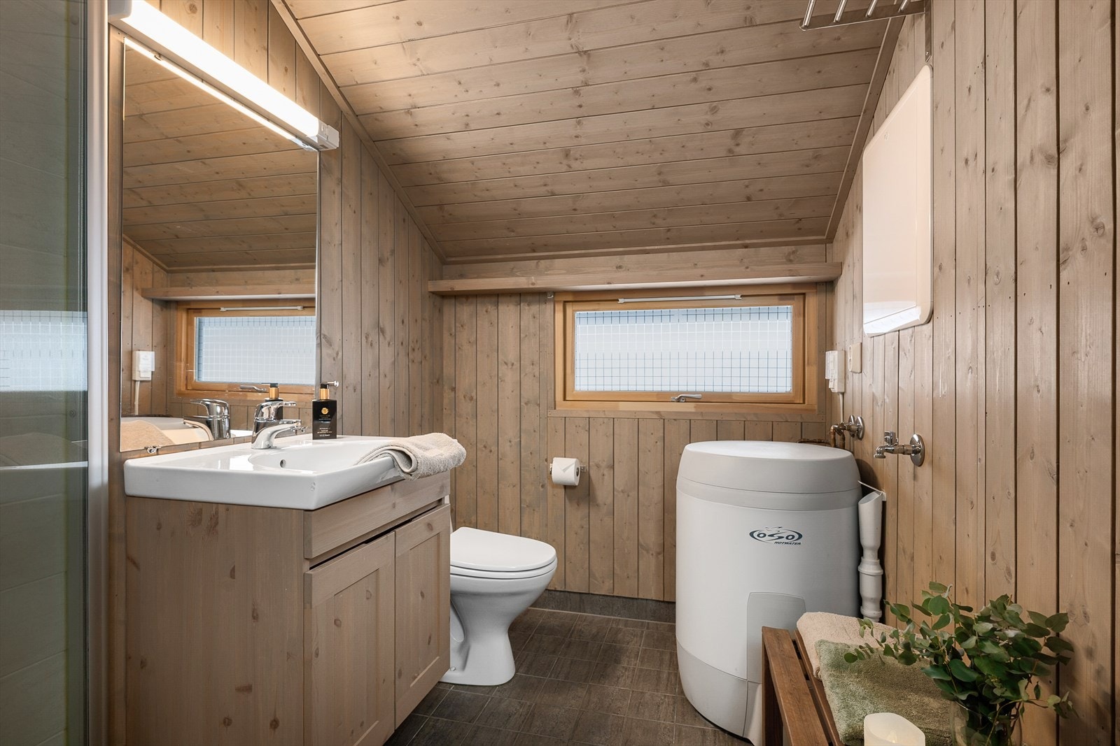 Funksjonelt bad med servant, dusj, WC og varmtvannsbereder. Flislagt gulv. Galleribilde