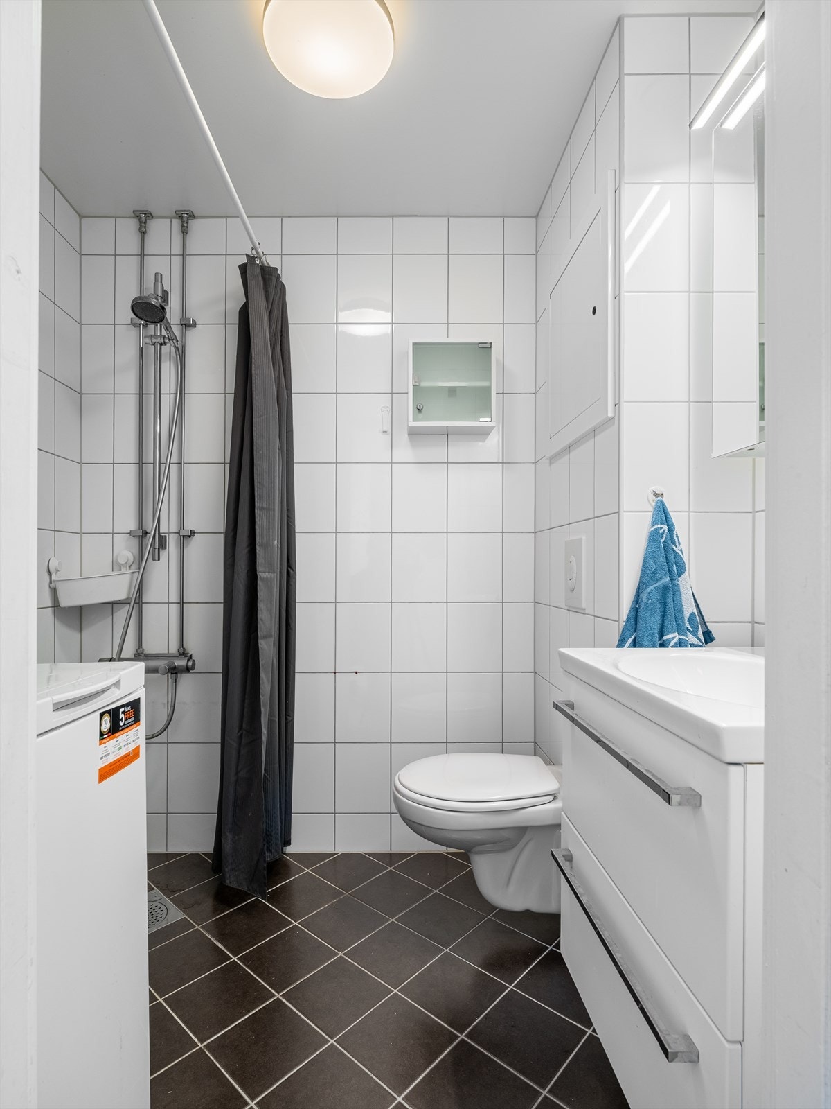 Badet er utstyrt med dusjhjørne, naturlig avtrekk, servant, servantskap, veggmontert wc, rørfordelingsskap og stoppekran Galleribilde