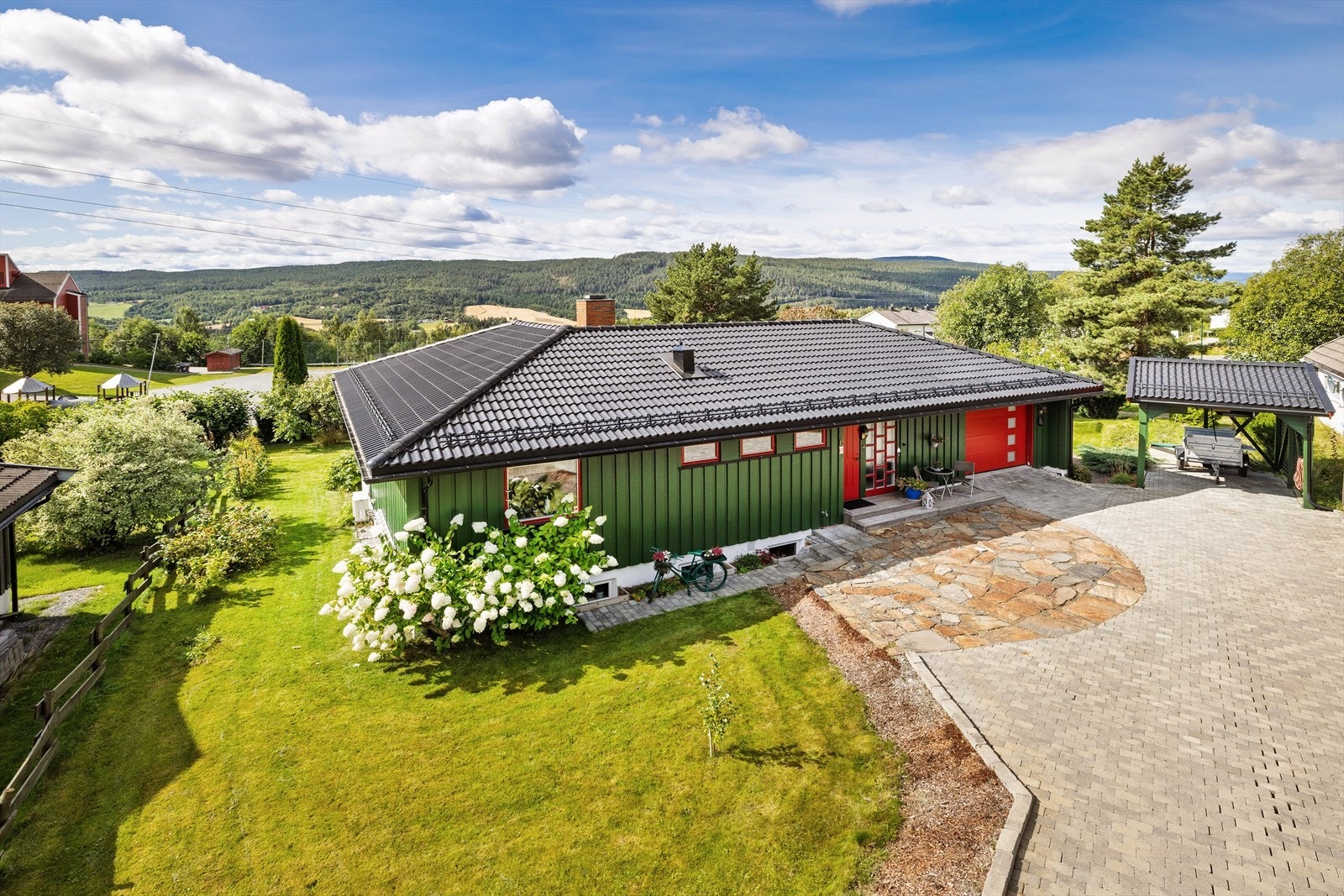 En innholdsrik enebolig med stor, belegningssteinbelagt gårdsplass, garasje og carport. Galleribilde