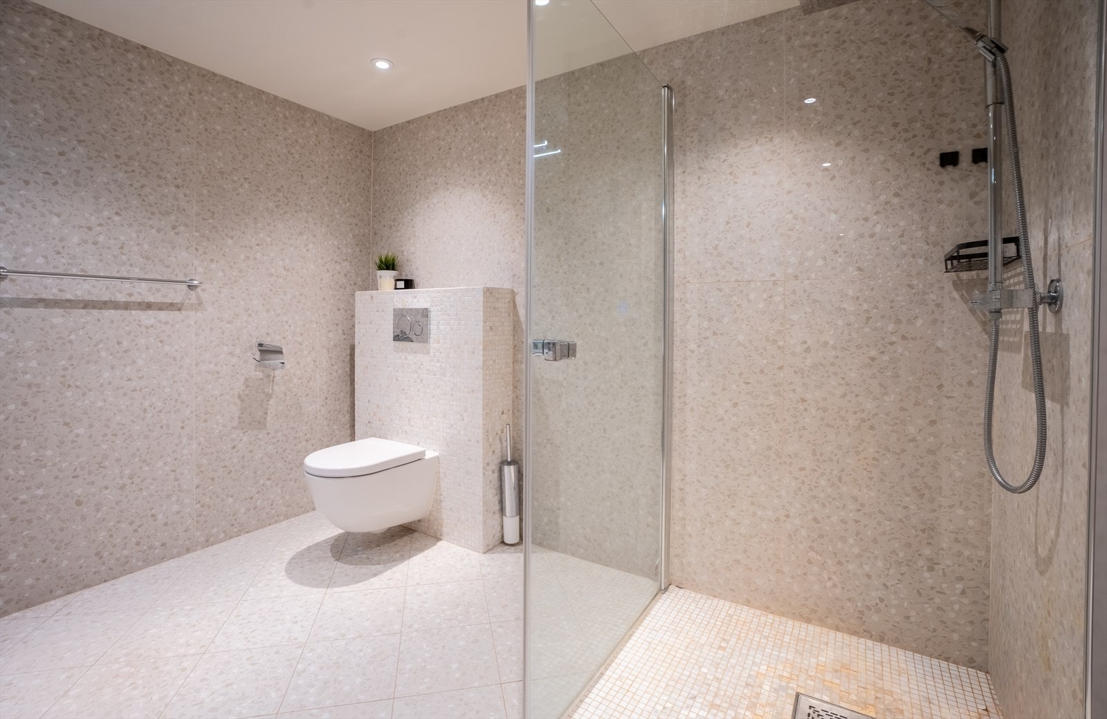 Badet er helfliset med varmekabler, og har innredning med to servanter, vegghengt toalett og dusjhjørne. Dette er badet til leiligheten til venstre. Galleribilde