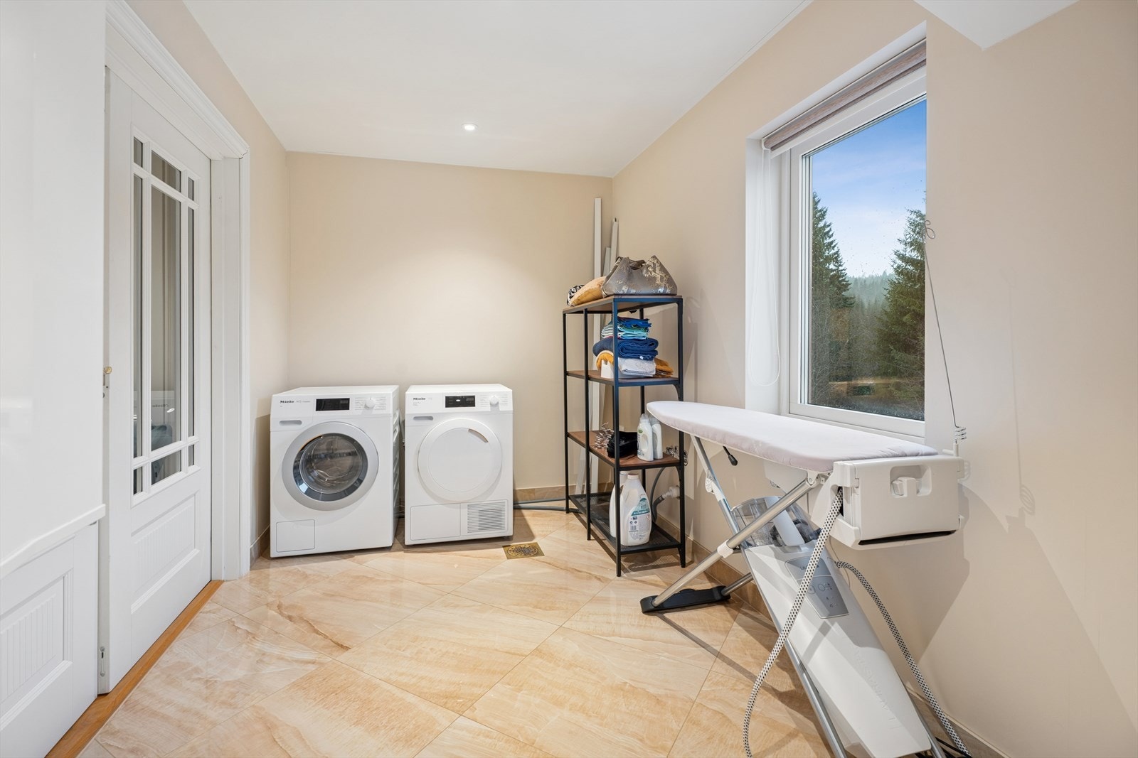 Et separat og praktisk vaskerom med flislagt gulv med varmekabler og opplegg for vaskemaskin. Rommet har balansert ventilasjon, og sentralenheten til sentralstøvsugeren er plassert her. Galleribilde