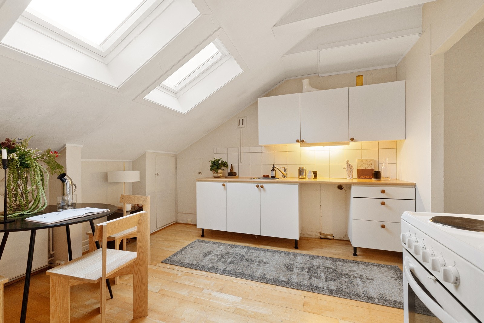 Separat kjøkkeninnredning med hvite glatte fronter og 28mm tykk laminatbenkeplate med nedfelt vaskekum i børstet stål og ettgreps krummet armatur fra Oras. Galleribilde