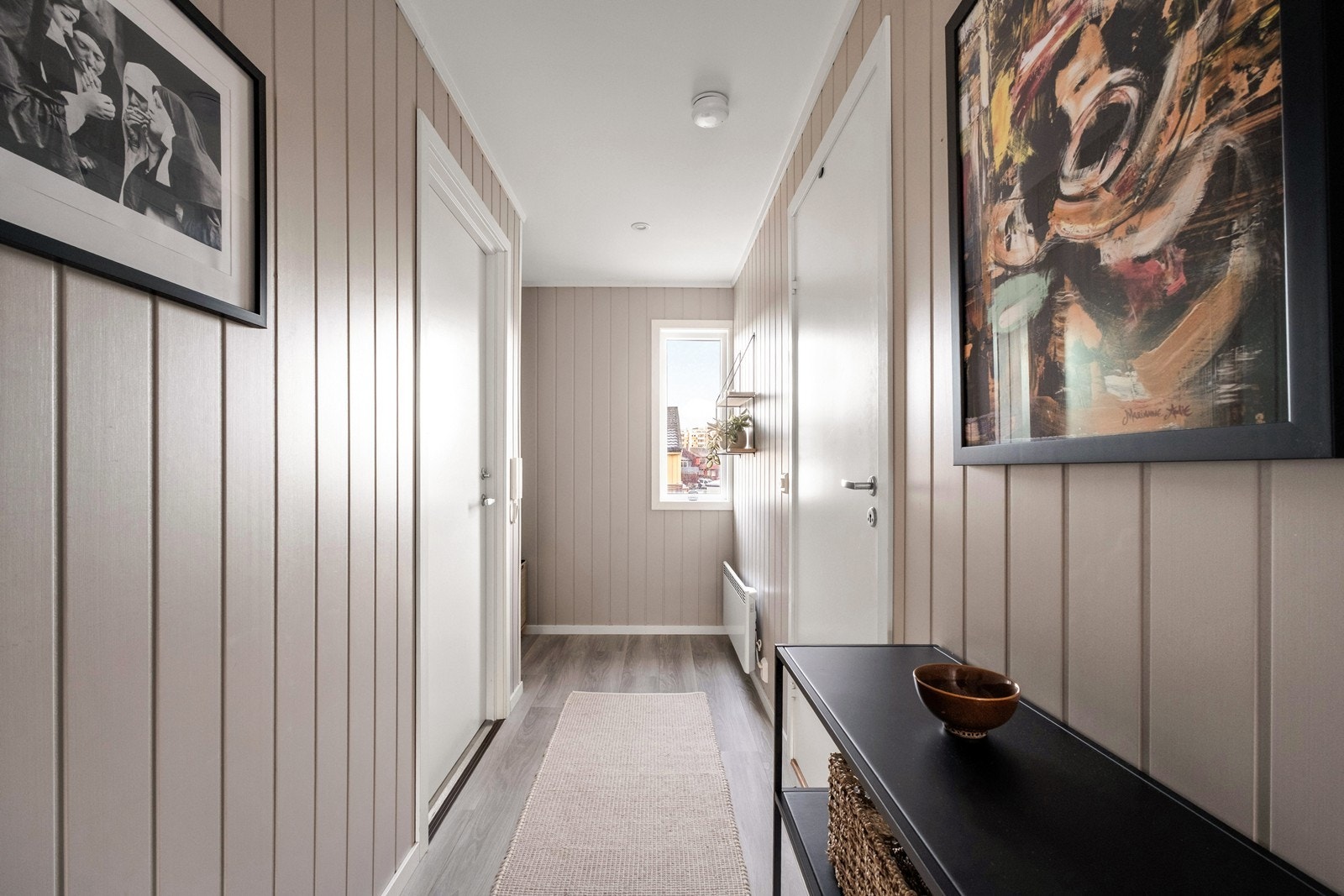 Entréen har laminatgulv og malt panel, med naturlig lysinnslipp fra vindu. Galleribilde
