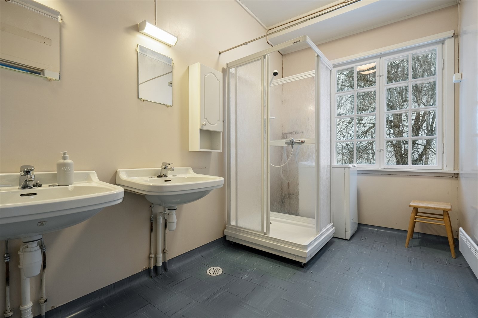 Badet har betonggulv med linoleumsflis og slette malte vegger - Her finner du dusjkabinett, to servanter på vegg og opplegg for vaskemaskin Galleribilde