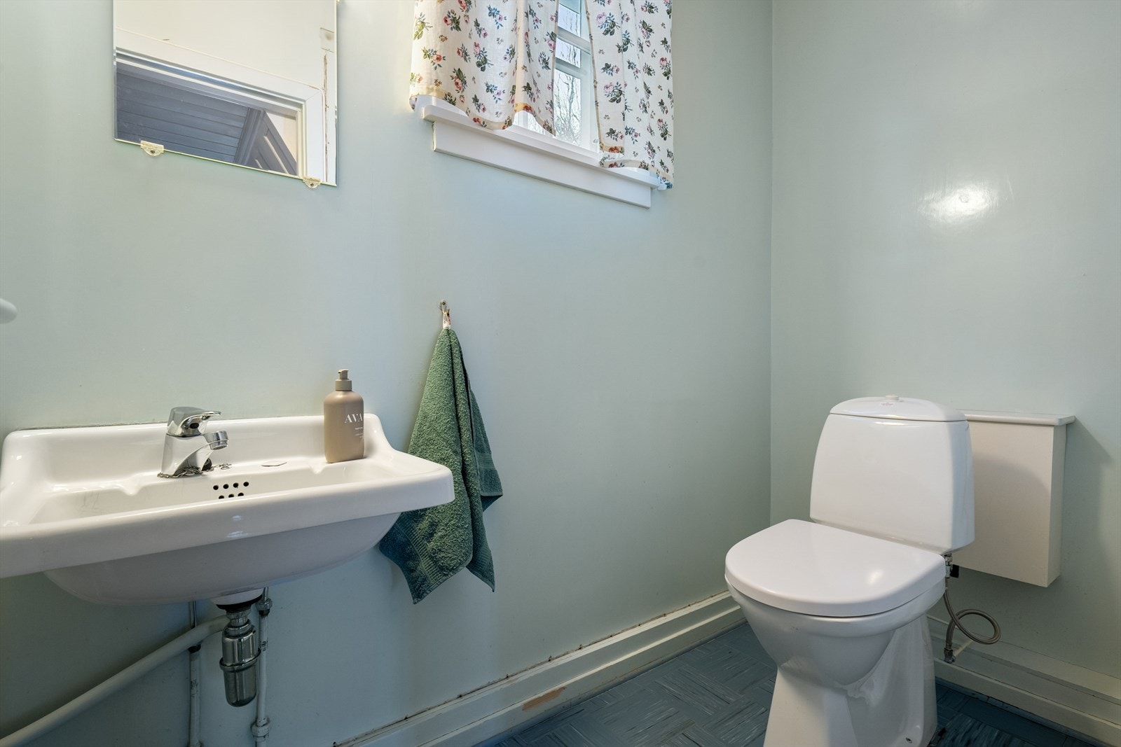 Vegg i vegg med badet er det separat toalettrom med gulvstående toalett og servant på vegg Galleribilde