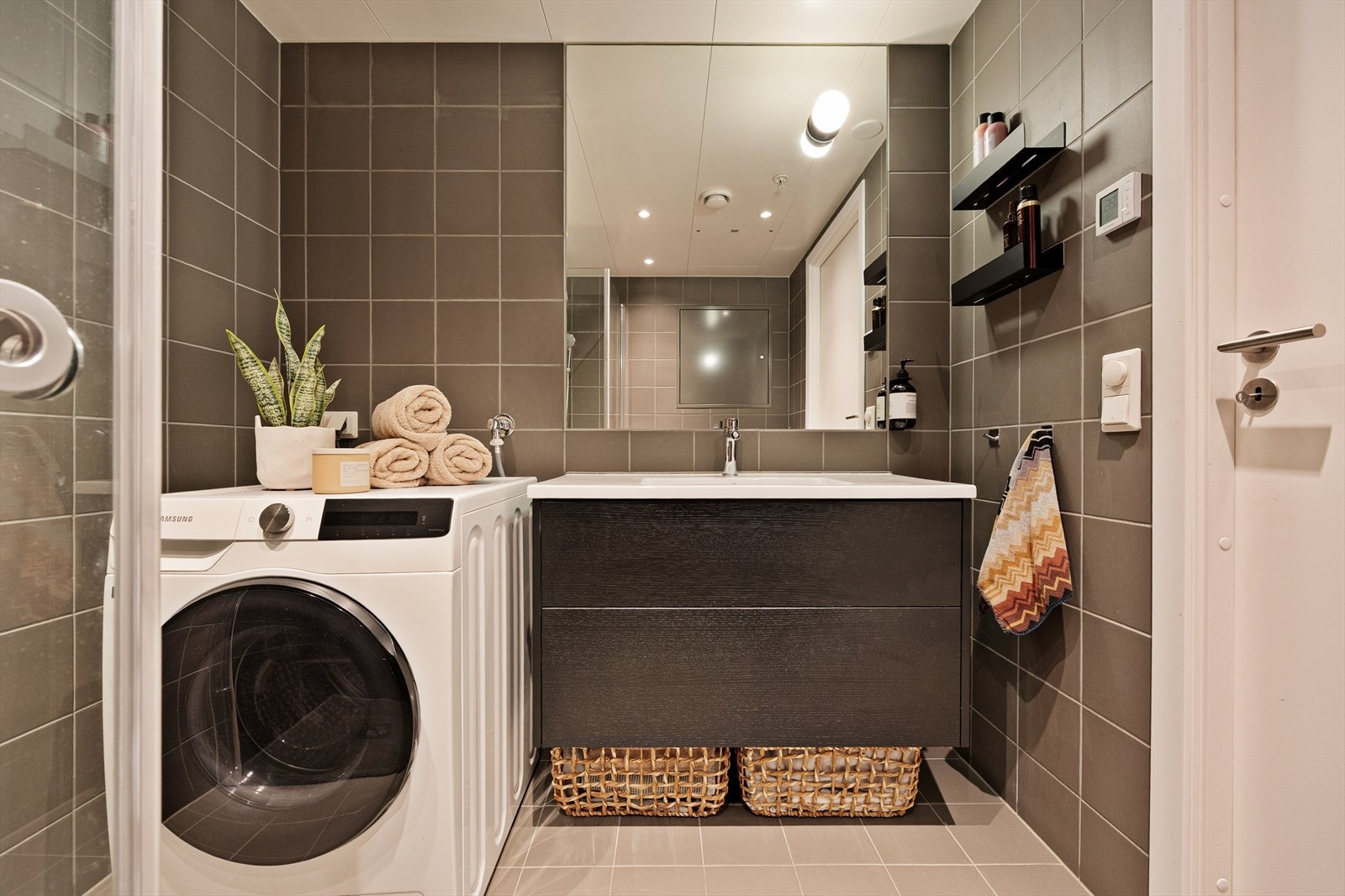 Innredningen består av helservant på vegghengt skuffeseksjon, vegghengt toalett og dusjhjørne med innfelle dusjdører. Opplegg for vaskemaskin. Galleribilde