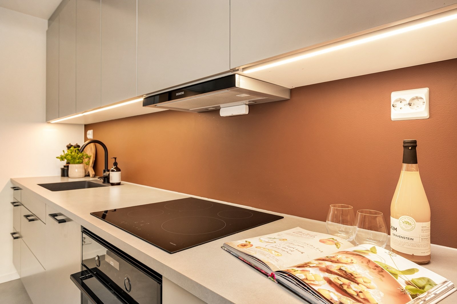 Veggen mellom benk og overskap er malt i en lekker kontrastfarge som står i stil til innredningen. Det er montert belysning under overskap. Galleribilde