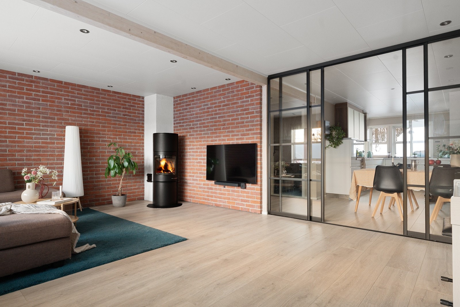 Vedovnen sikrer hygge og kos på kalde kvelder. Det er etablert et glassdører mellom kjøkken og stue som fungerer som en pen rominndeler. Galleribilde
