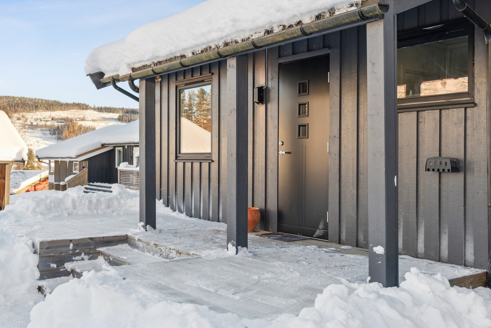 Inngangsparti med åpen veranda mot nord, der morgensola varmer uteplassen om sommeren. Yttervegger ble sist overflatebehandlet rundt 2021. Galleribilde