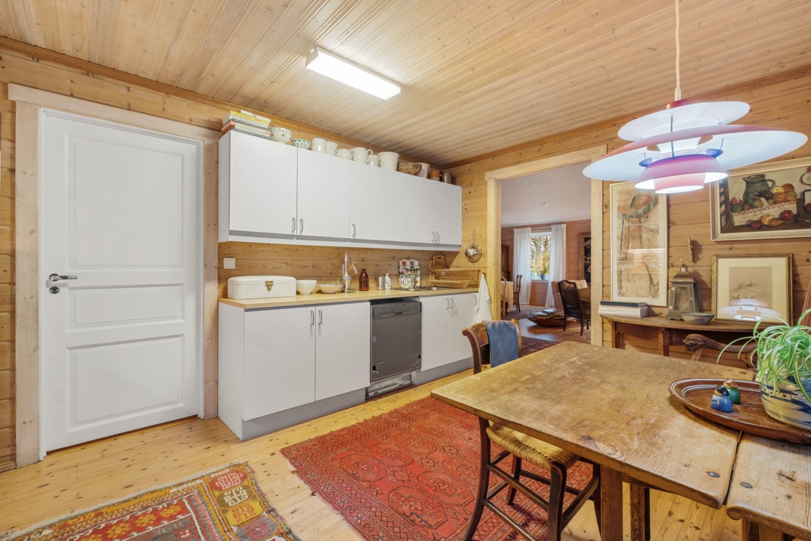 Kjøkken med profilerte furufronter, godt utstyrt med benker og overskap. Fliser under overskap, benkeplate med nedfelt servant. Plass til kjøleskap, oppvaskmaskin og komfyr, med avtrekk fra komfyrplass. Galleribilde