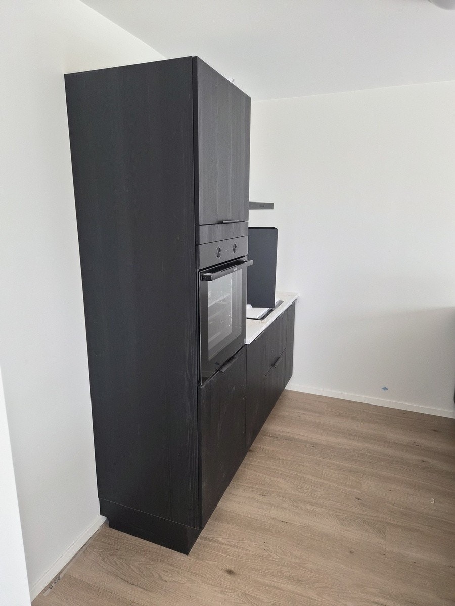 Kjøkken - sort design med hvite platertopper. Integrert Komfyr, induksjon og oppvaskmaskin Galleribilde