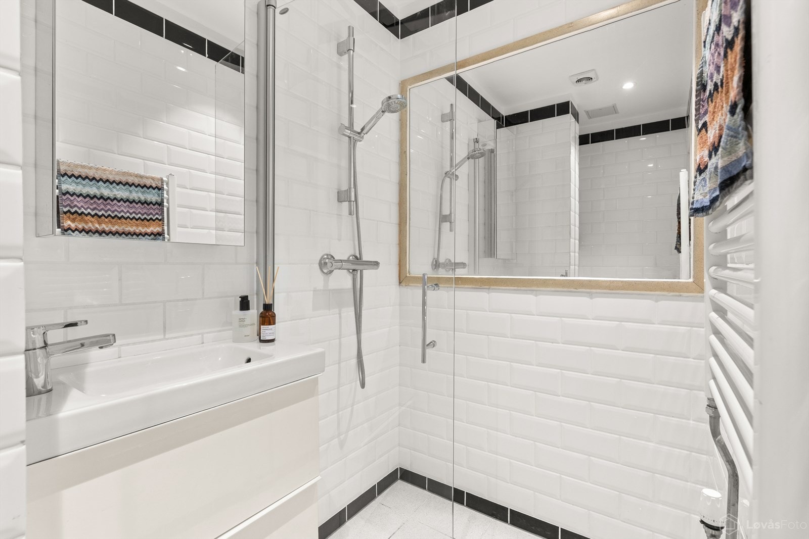 Delikat, flislagt bad med dusjhjørne i glass og vegghengt servant. Galleribilde