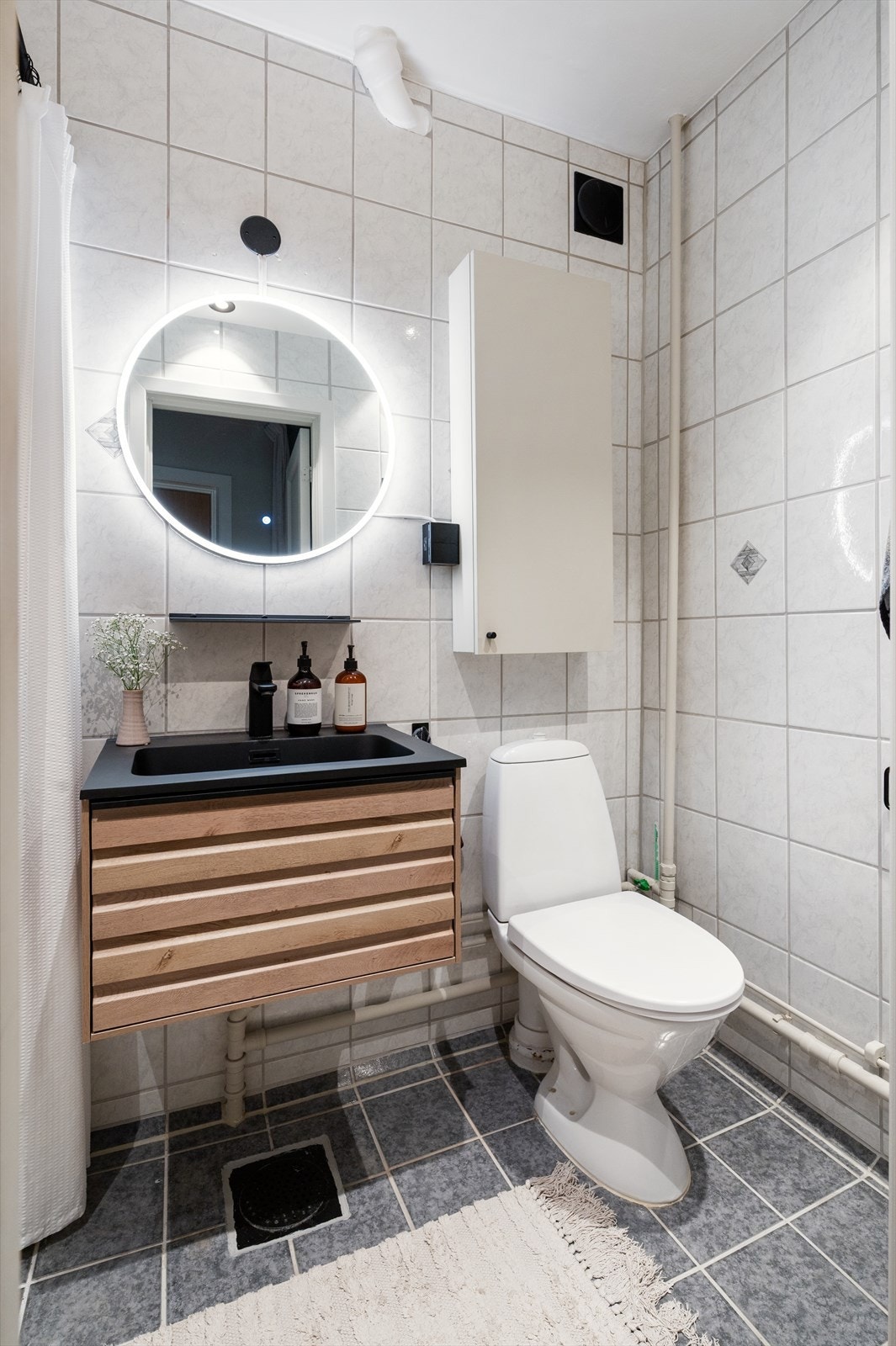 Badet er innredet med servant med servantskap, speil, vegghengt hylle og toalett. Galleribilde