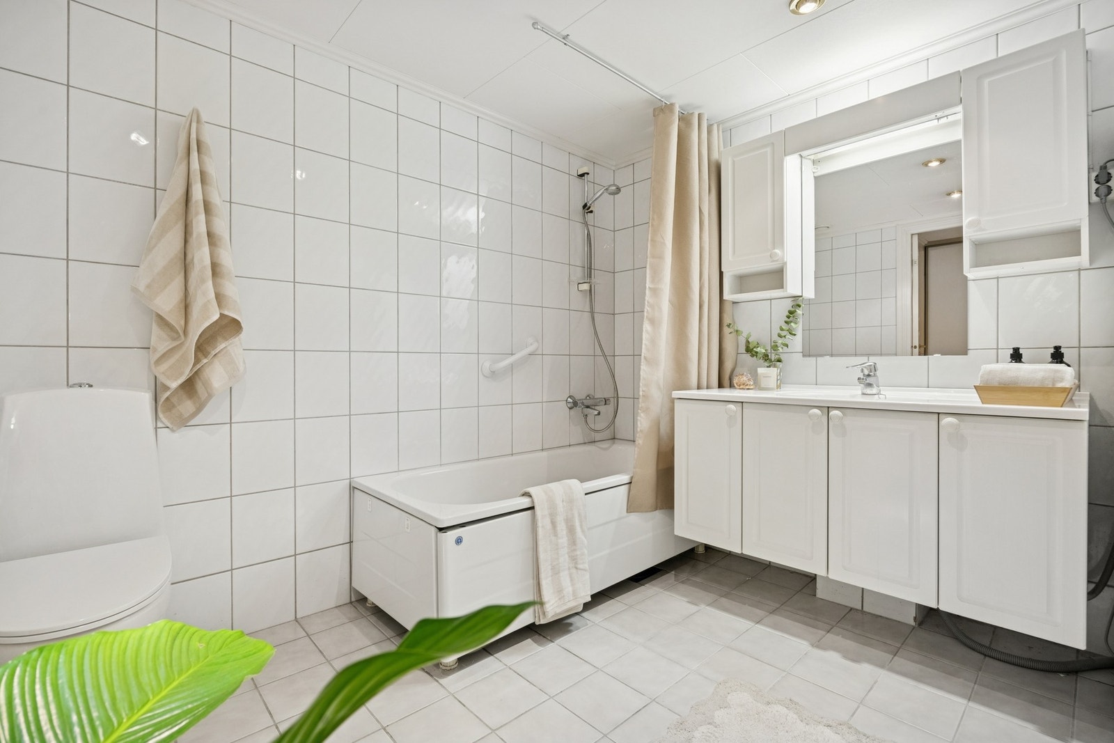 Innredet med badekar med dusjgarnityr montert på vegg og opplegg for vaskemaskin. Galleribilde