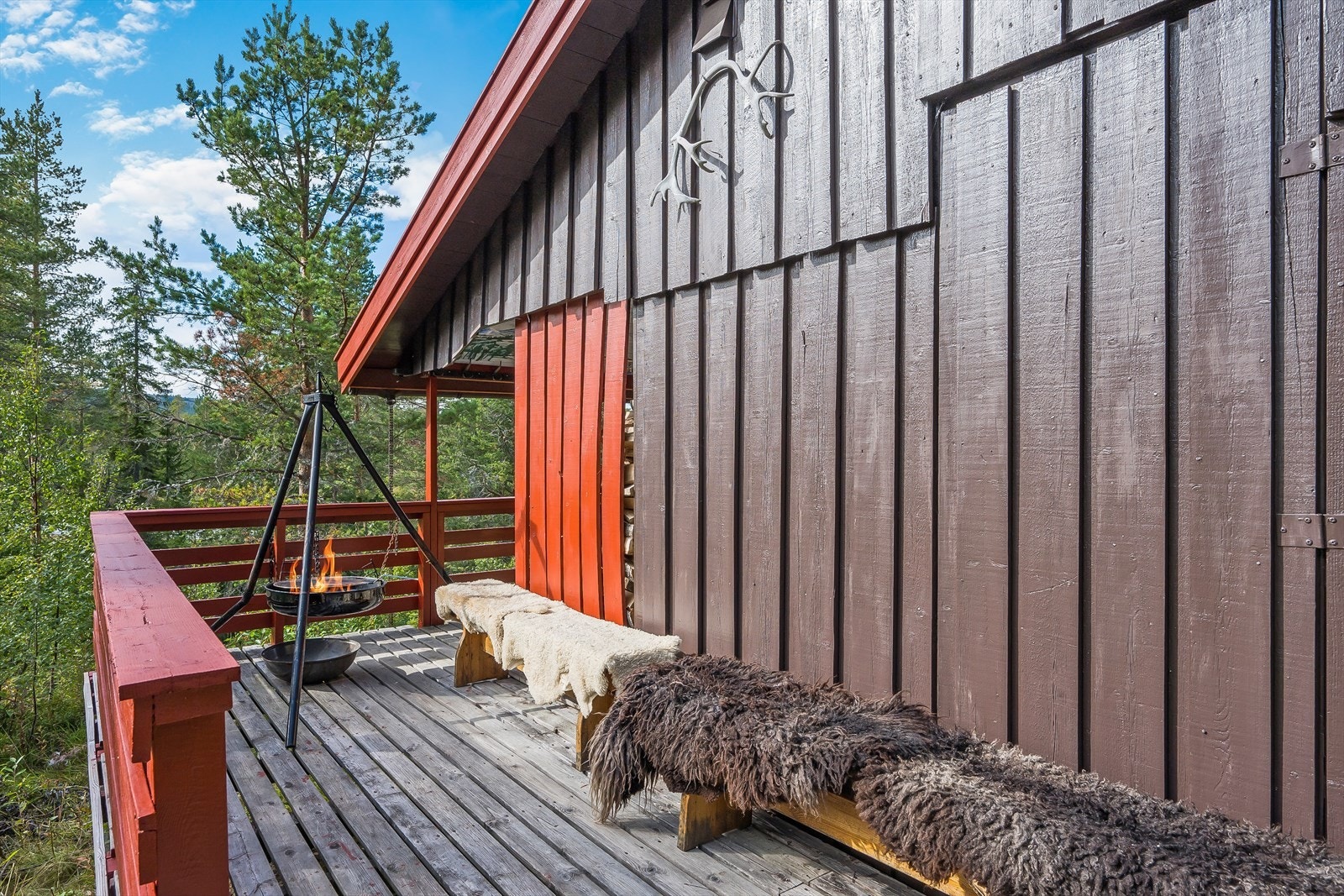 Terrassen strekker seg videre rundt hjørnet av hytta, med en koselig og skjermet uteplass i endeveggen. Galleribilde