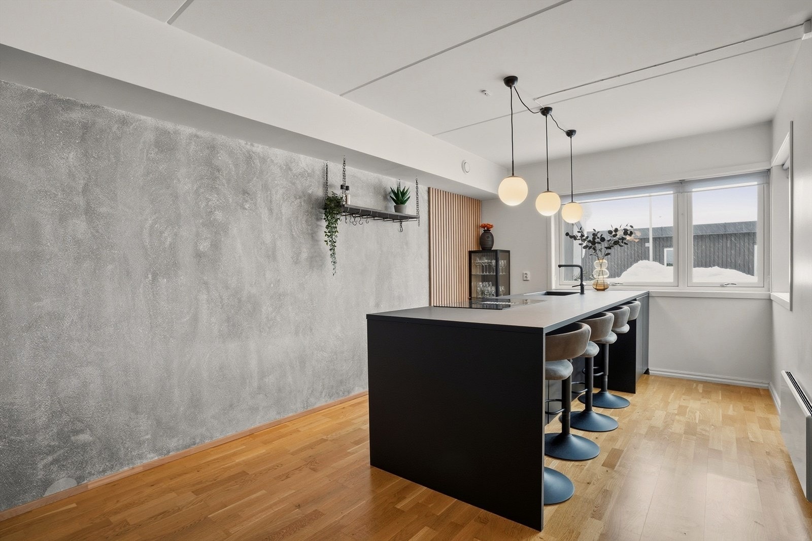 Inredningen er utført i mørke, tidløse materialer som kombineres elegant med den rå betonginspirerte veggen og vertikale trepaneldetaljer. Galleribilde