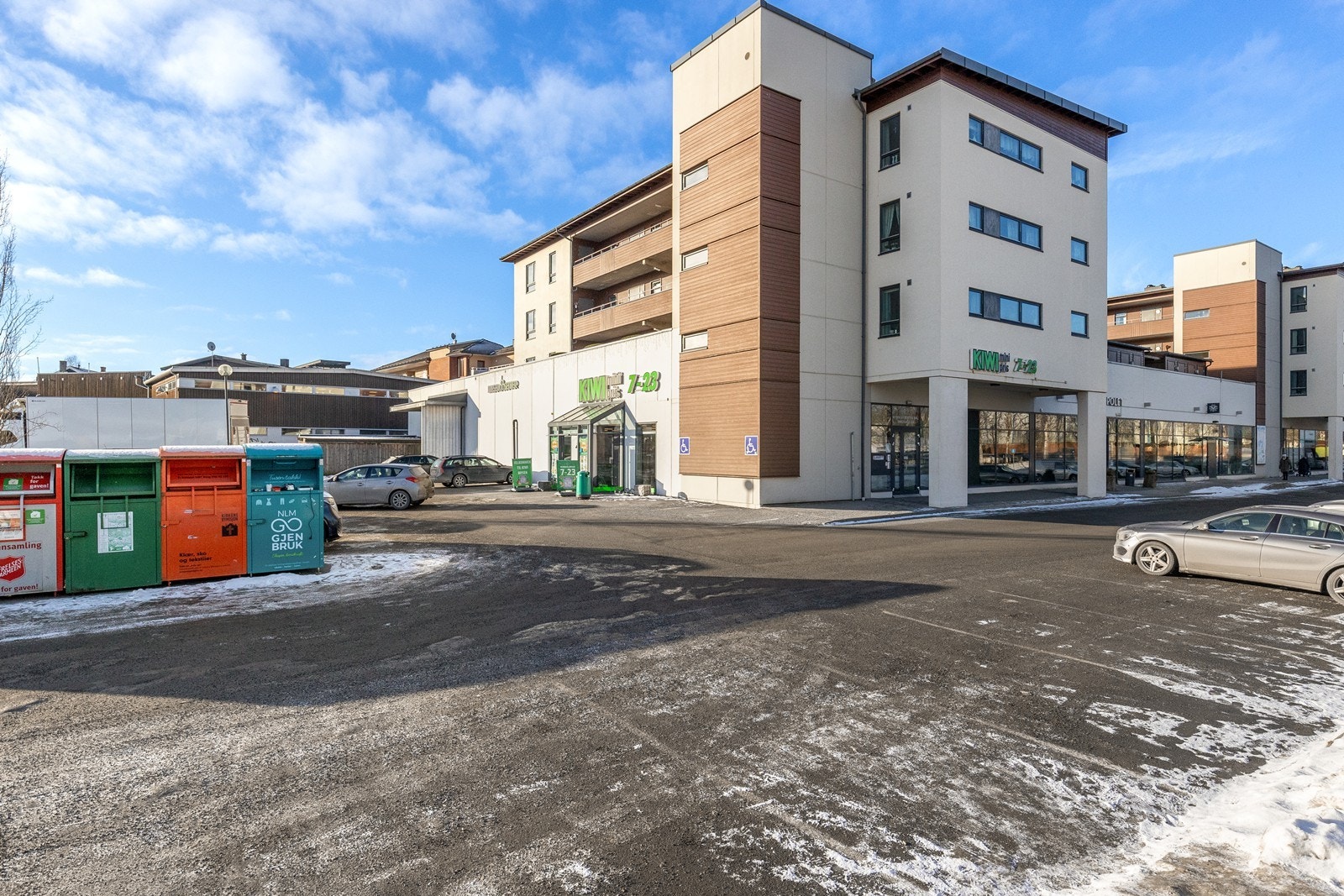 Nærbutikk med parkeringsplass, en del av et større boligkompleks. Galleribilde