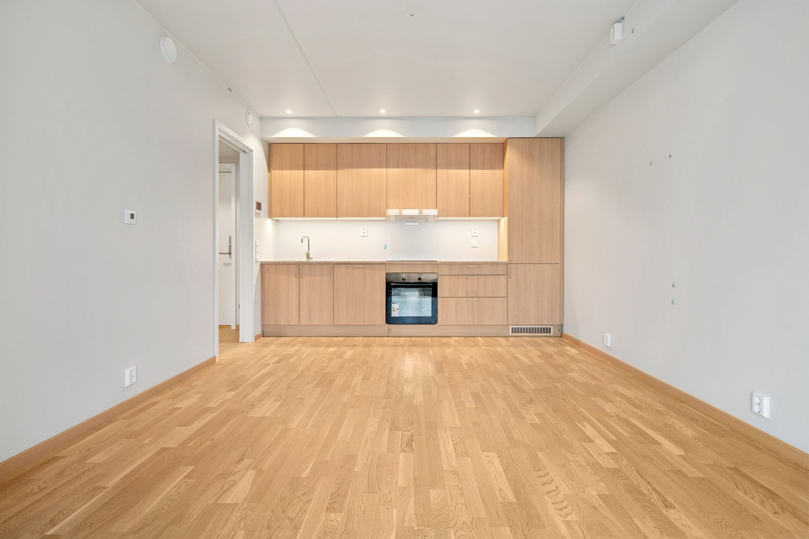 Moderne kjøkkeninnredning med glatte laminerte fronter. Det er integrert komfyr, koketopp, kjøl/fryseskap, oppvaskmaskin og waterguard. Galleribilde