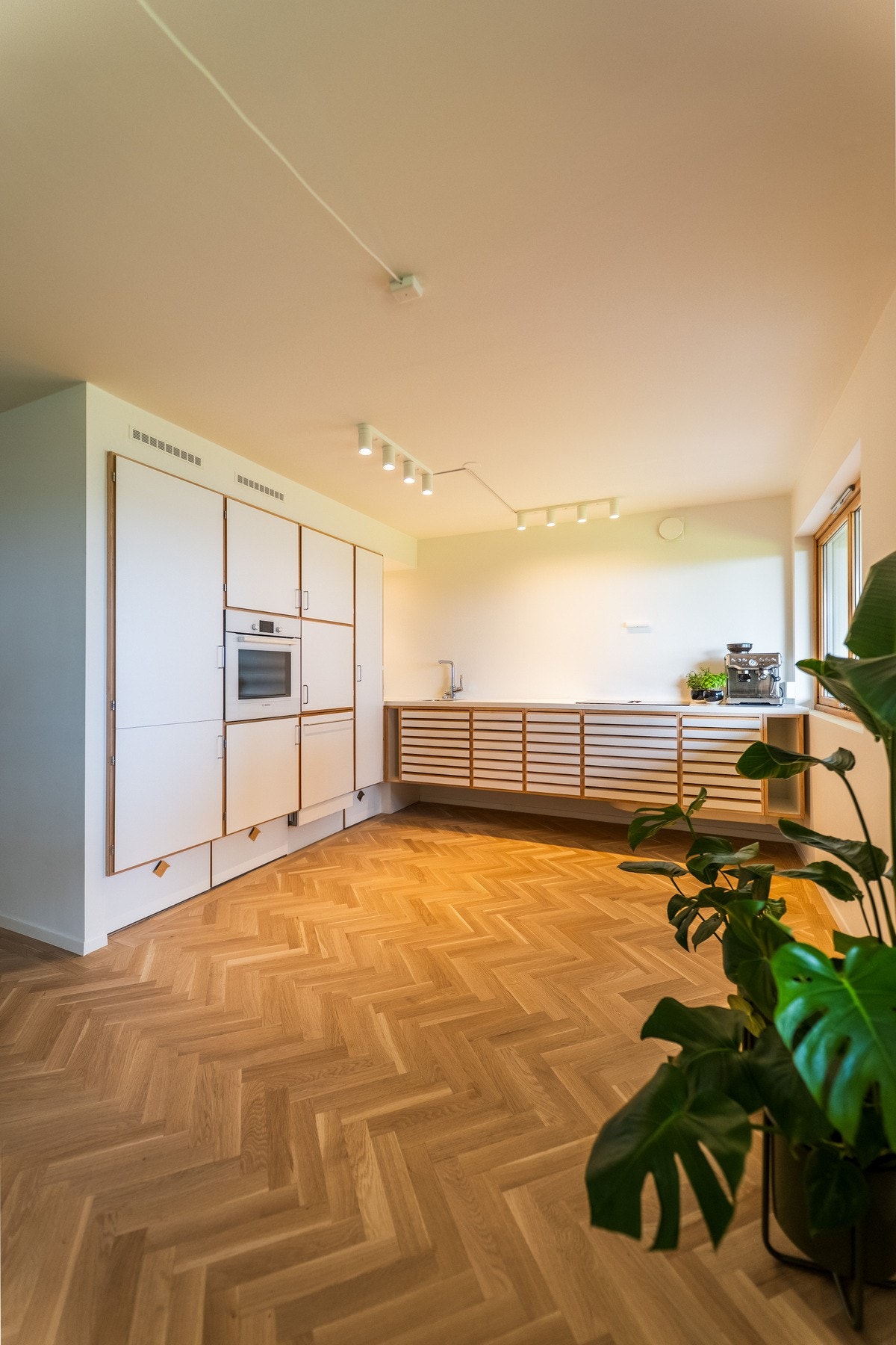 Den elegante helveggen med integrerte skap gir kjøkkenet et ryddig og gjennomført uttrykk. Galleribilde