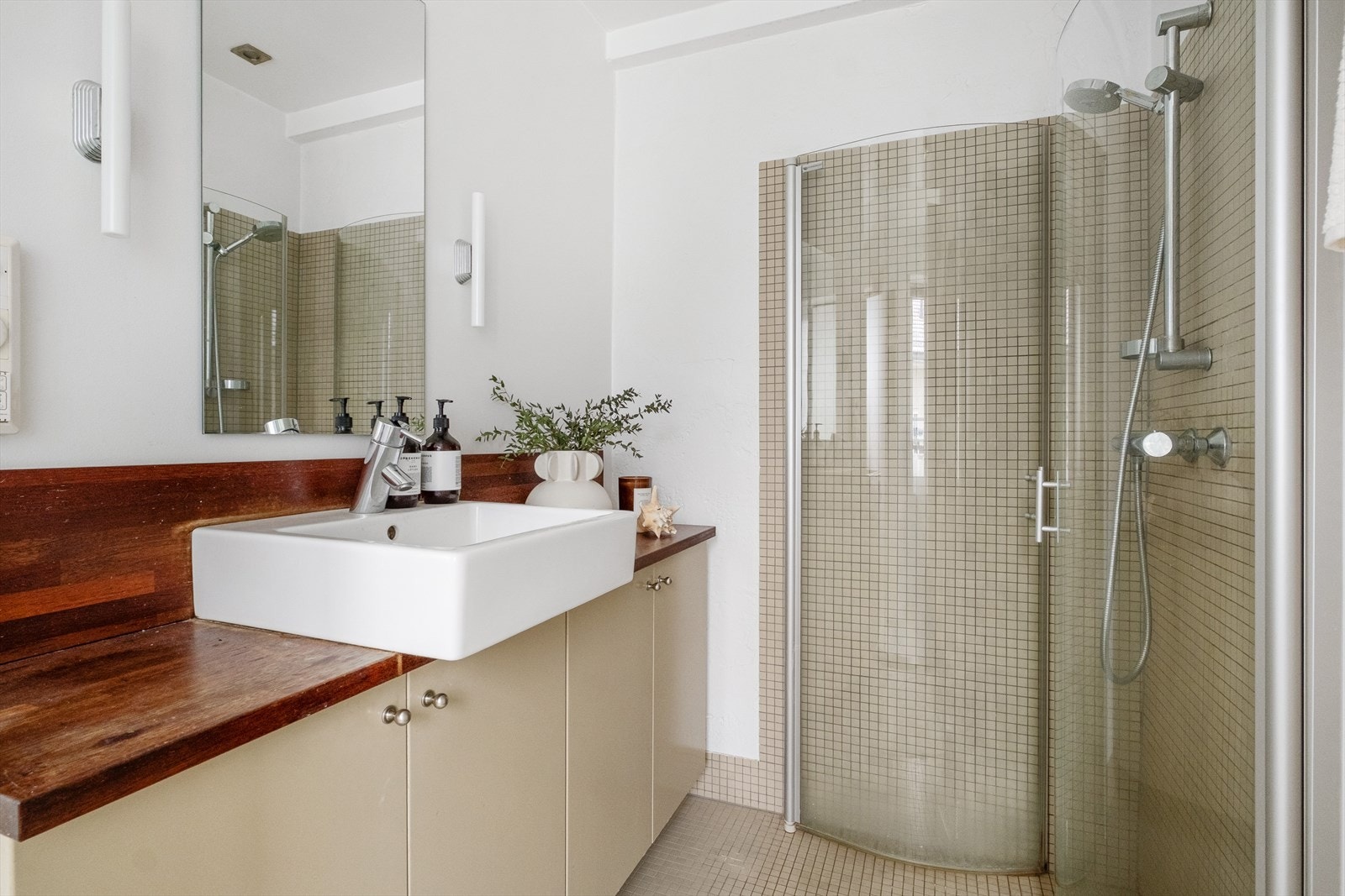 Stilig bad i åpen løsning mot soverommet. Badet har flislagt gulv, samt en kombinasjon av flis og malte flater på veggene. Galleribilde