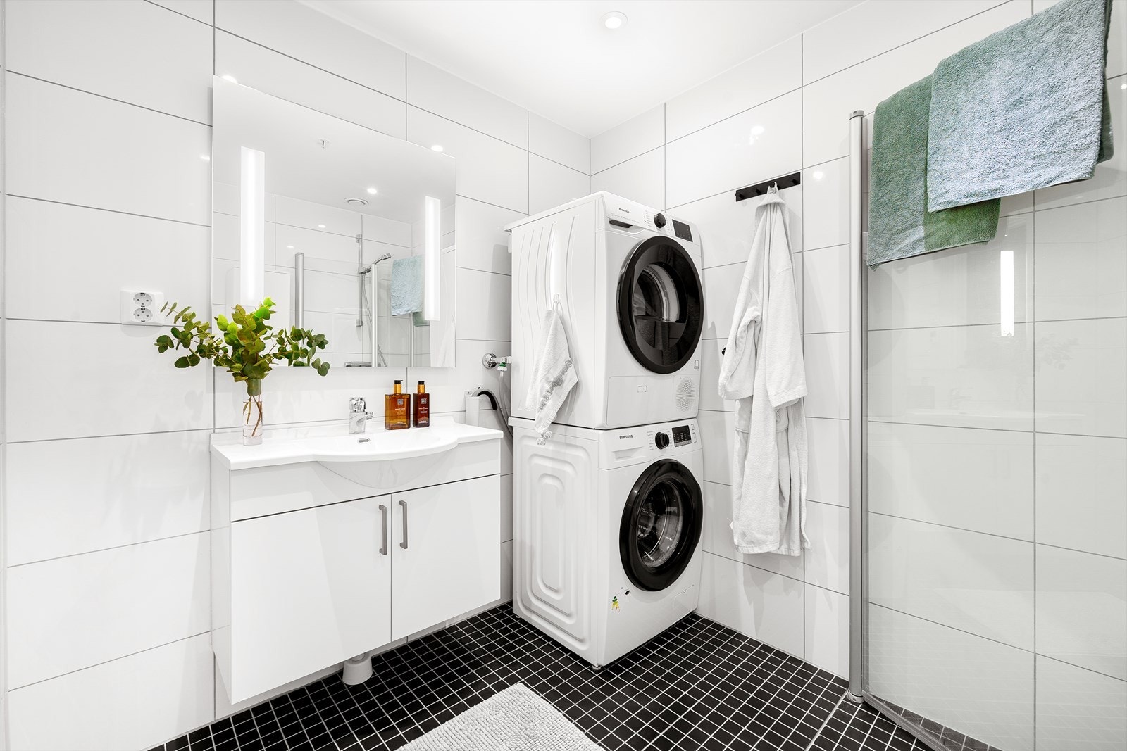 Baderommet er på ca. 4,5 m² og fremstår som delikat, med helflisede overflater på gulv og vegger. Innfelte spotter i taket gir et eksklusivt og moderne uttrykk, mens elektrisk gulvvarme sørger for ekstra komfort og en behagelig start på dagen. Galleribilde