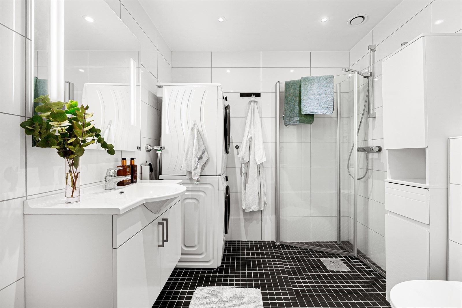 Badet er funksjonelt utstyrt med innfellbare dusjdører/dusjhjørne, veggmontert toalett, servant med tilhørende skap, mekanisk avtrekk, rørfordelerskap, stoppeventil, vannmåler, styringspanel til ventilasjonsaggregatet, og opplegg for vaskemaskin. Galleribilde