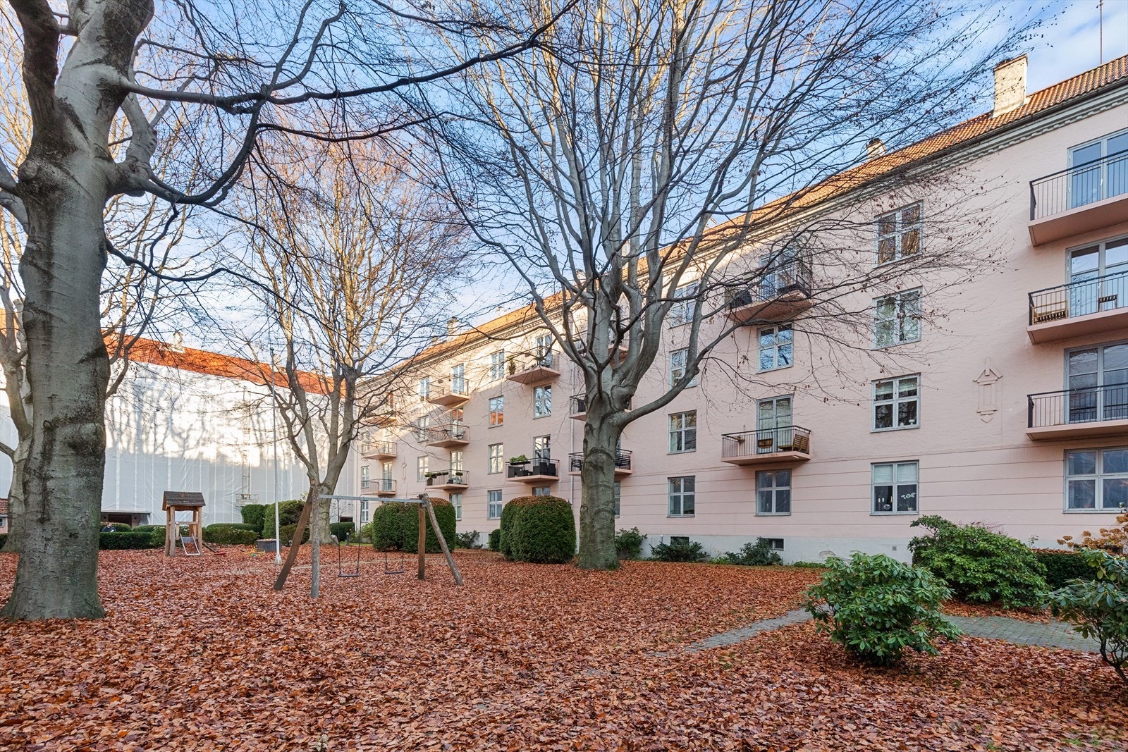 Pen og frodig bakhage med lekeapparater og hyggelige fellesarealer. Galleribilde