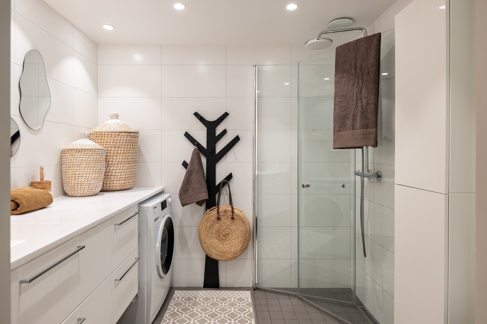 Baderommet er utstyrt med innfellbare dusjvegger og regndusj, innredning med servant, opplegg for vaskemaskin og vegghengt toalett. Galleribilde