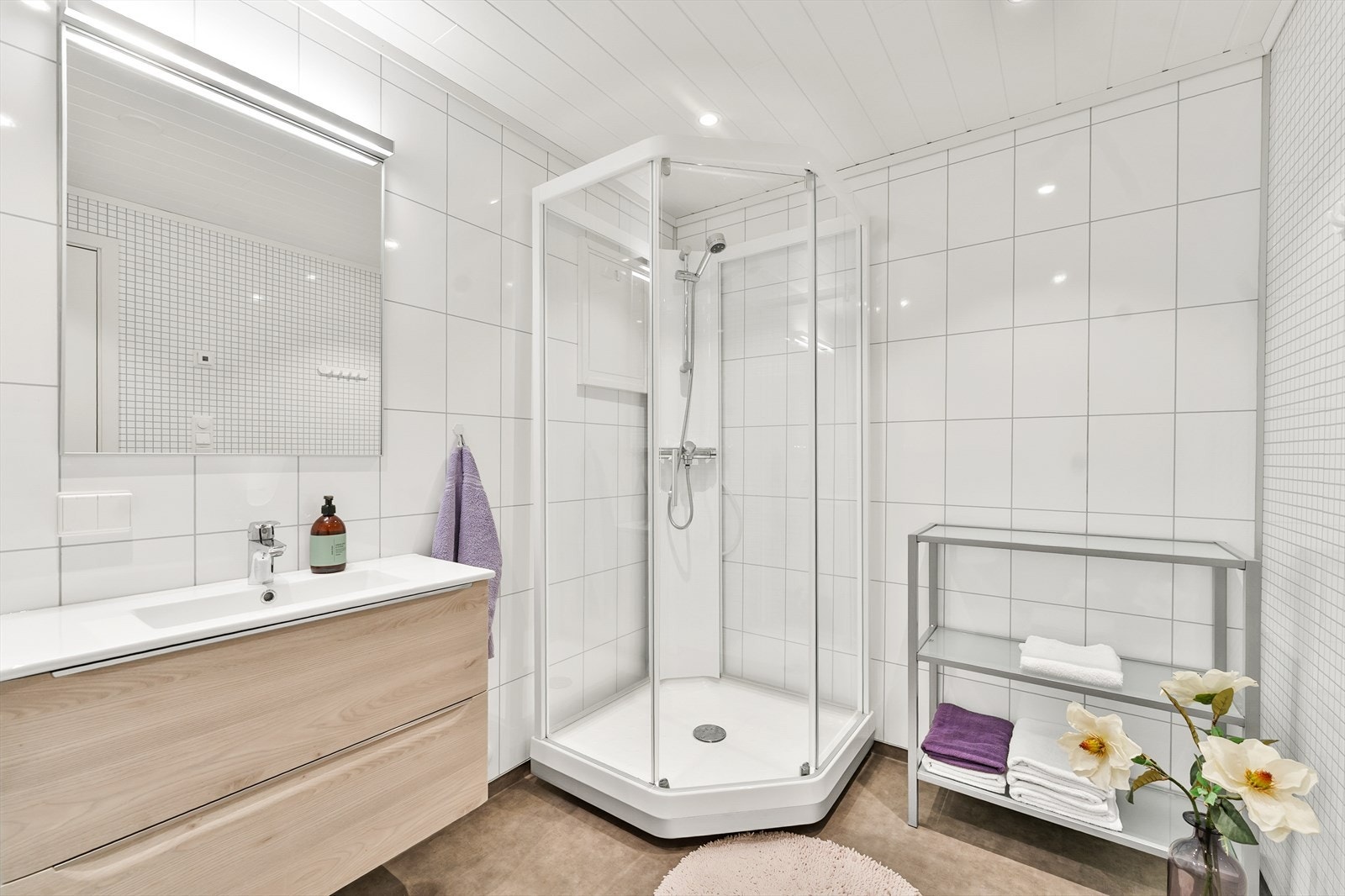 Lyst og moderne bad, innredet med nedfelt servant, dusjkabinett og vegghengt toalett Galleribilde