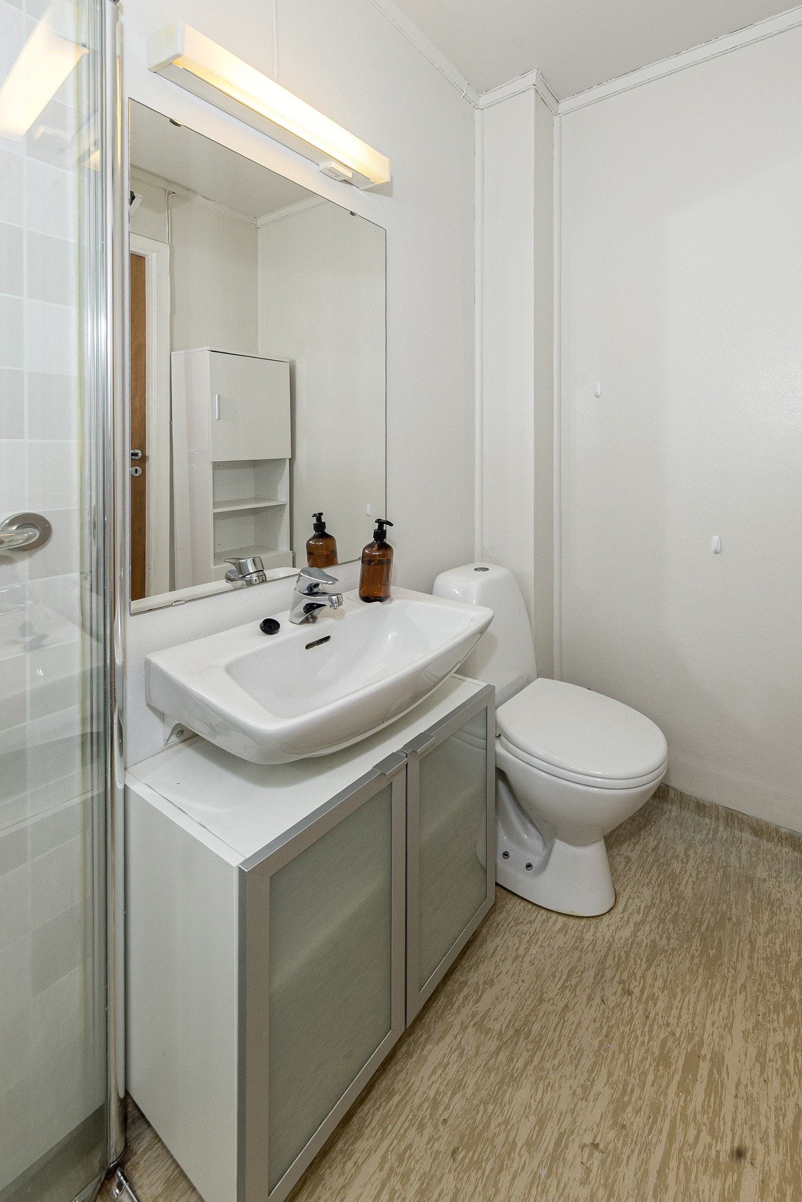 Badet har servant m/underskap og speil, toalett og høyskap Galleribilde