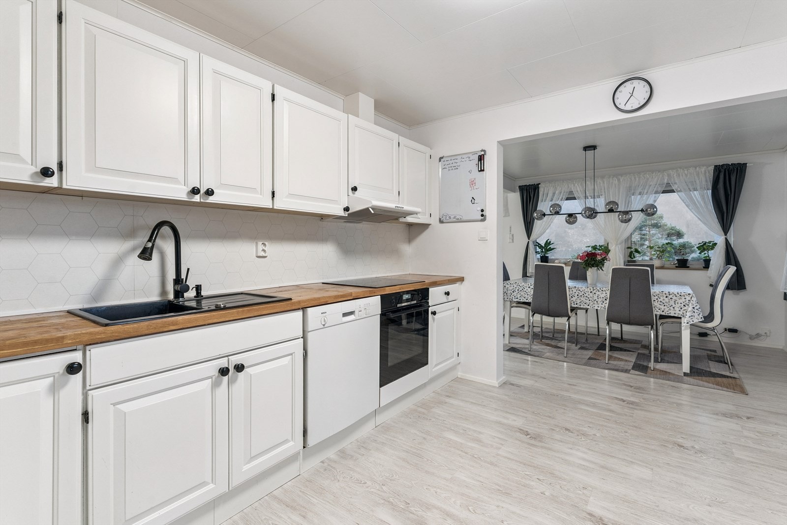 Kjøkkenet har kvit innreiing med profilerte frontar og benkeplate i heiltre. Det er integrert steikeomn og induksjonstopp i innreiinga. Frittståande kjøleskap og oppvaskemaskin. Galleribilde