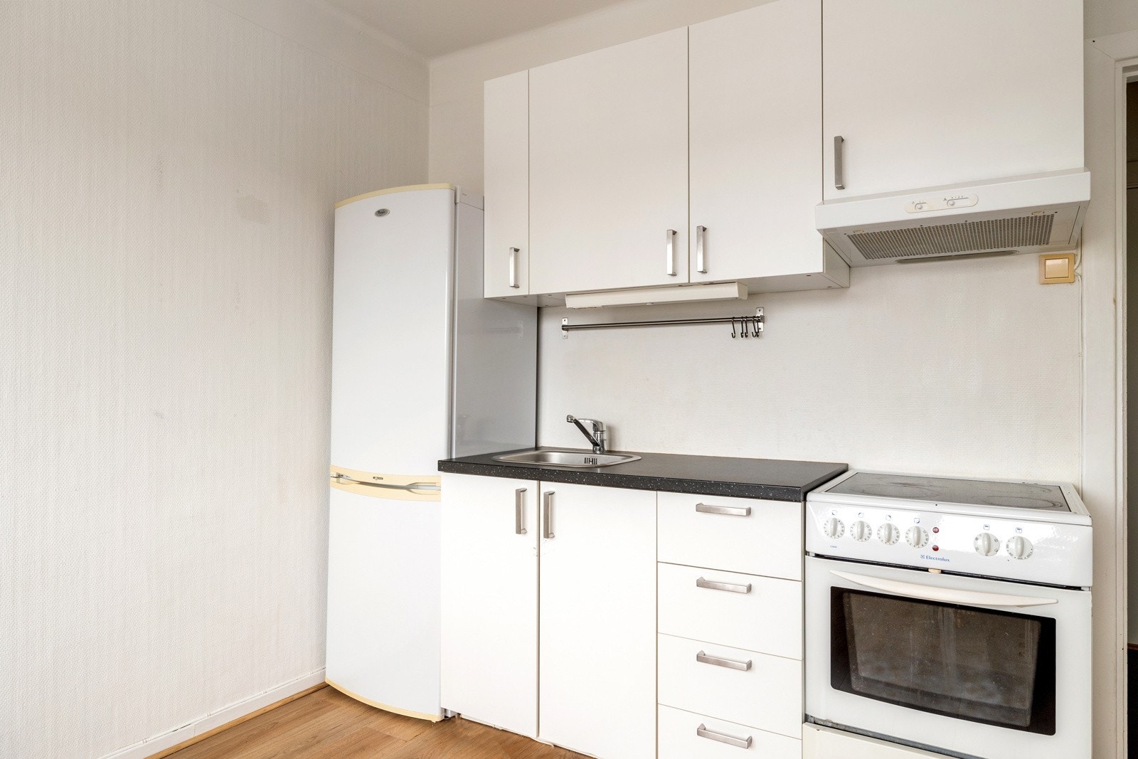 Kjøkkeninnredningen har glatte, hvite fronter og laminat benkeplate Galleribilde