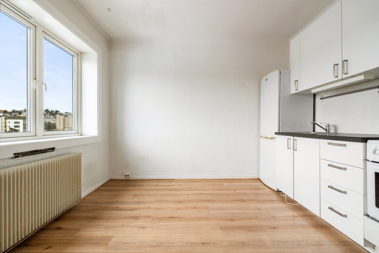 Leiligheten har et lyst oppholdsrom med store vindusflater som slipper inn rikelig med naturlig lys Galleribilde