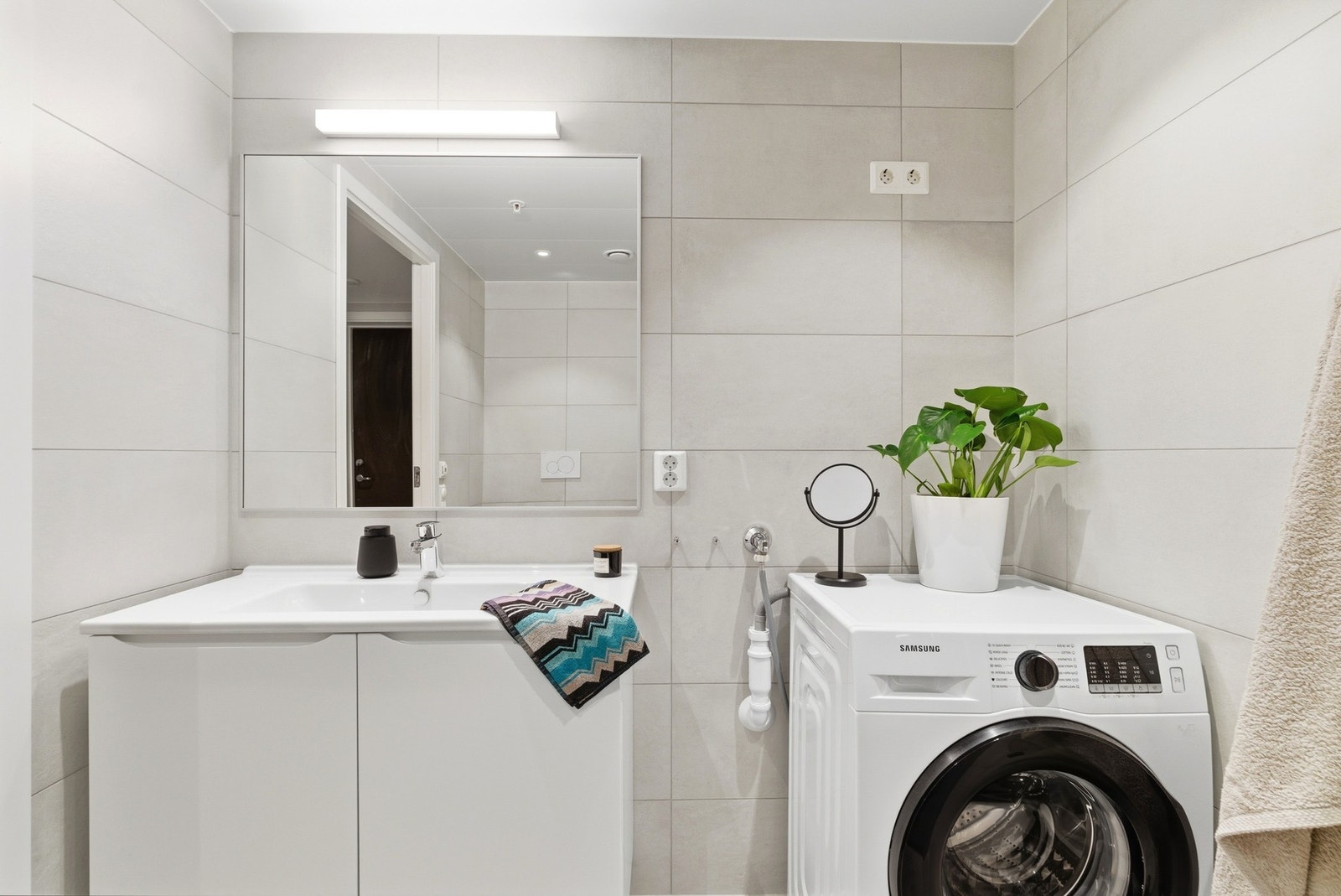 Servantinnredning og speil med lysarmatur over. Opplegg for vaskemaskin og tørketrommel. Galleribilde