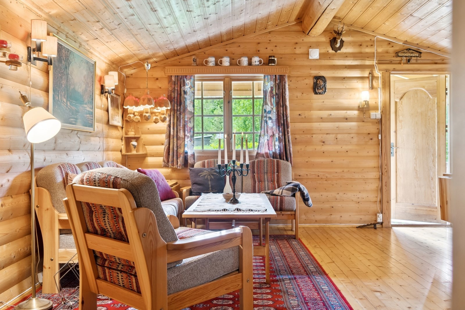 Stue med panelt skråhimling og tømmervegger skaper lun hytteatmosfære. Galleribilde