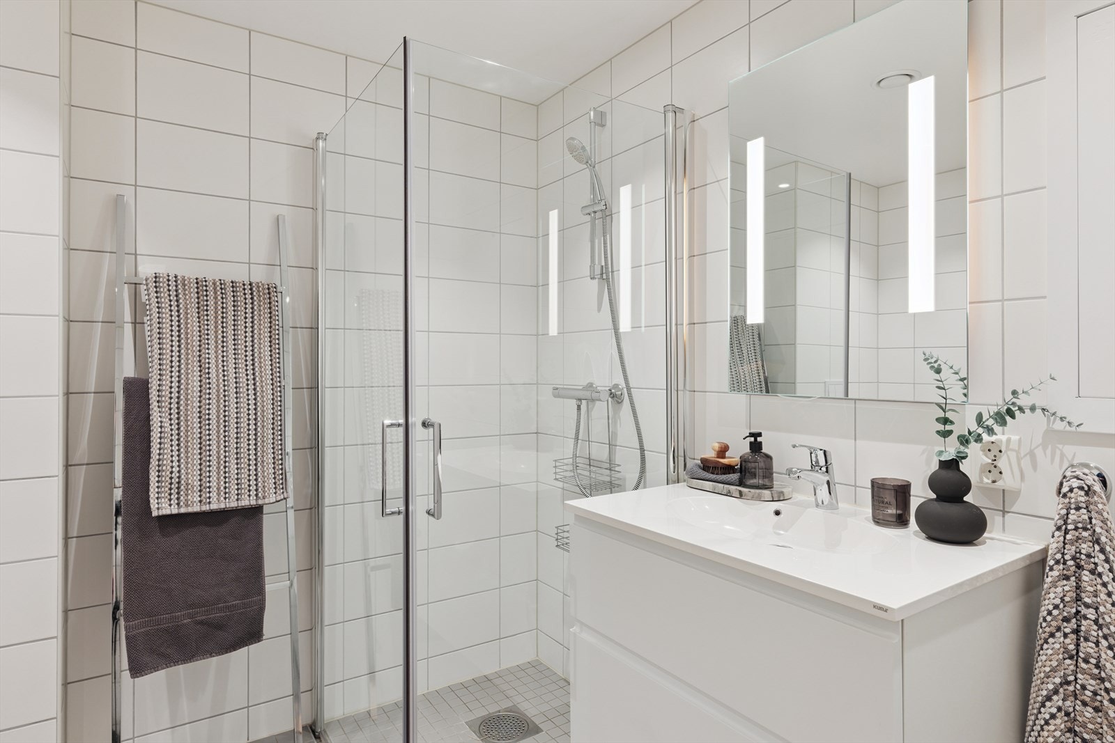 Servantskap, speil med integrert lys, dusjhjørne med dusjdører i herdet glass og vegghengt wc. Galleribilde