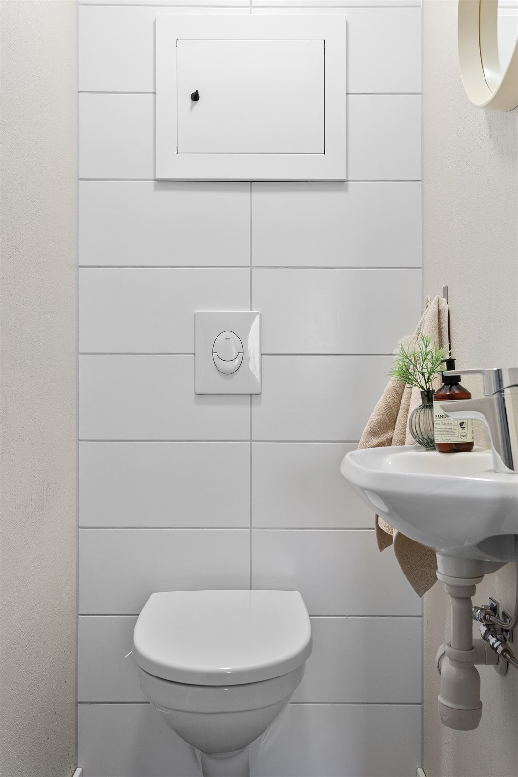 Toalettrom med flislagt gulv innredet med vegghengt toalett og servant. Galleribilde