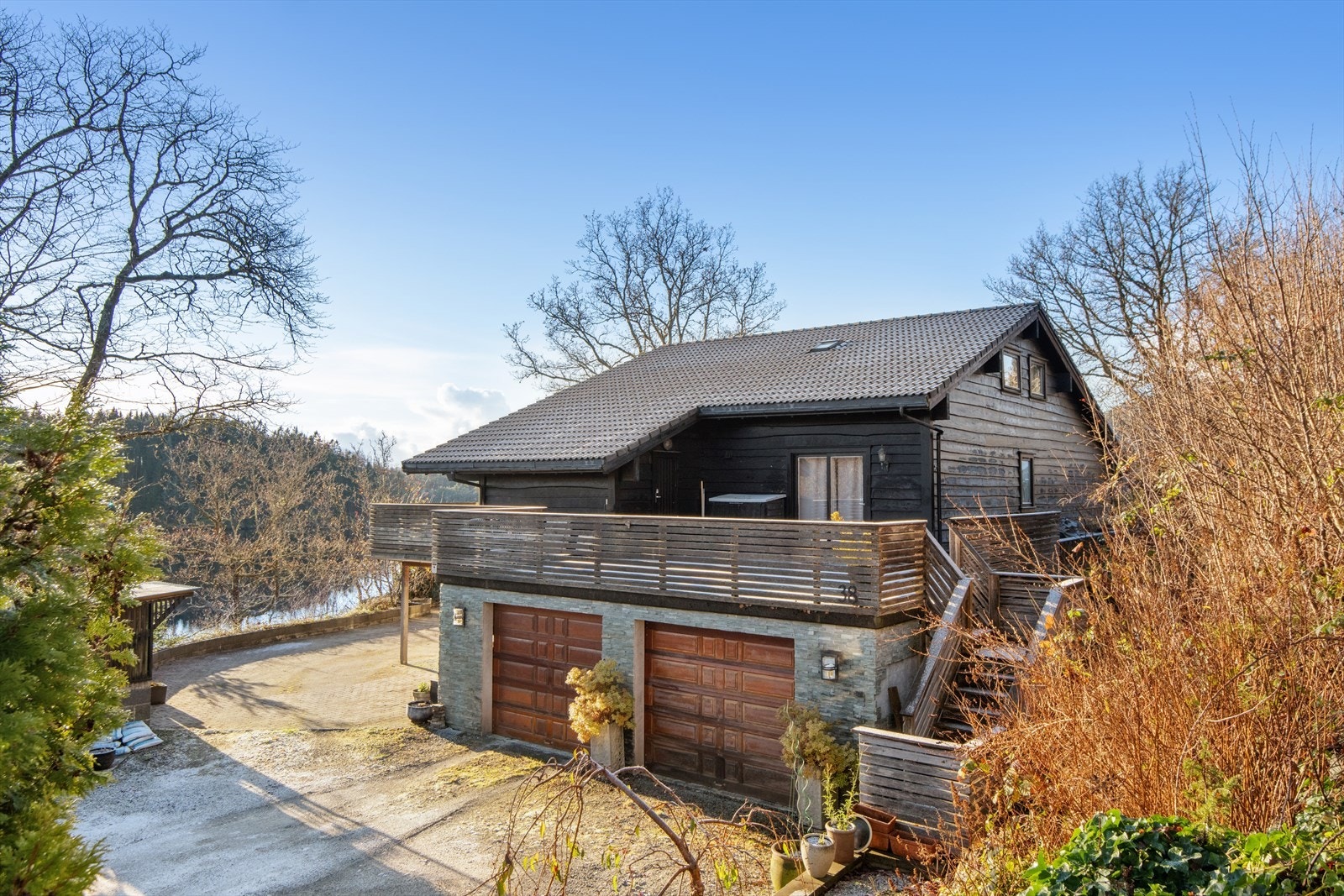 Boligen har dobbelgarasje med treporter og stor terrasse oppå. Galleribilde